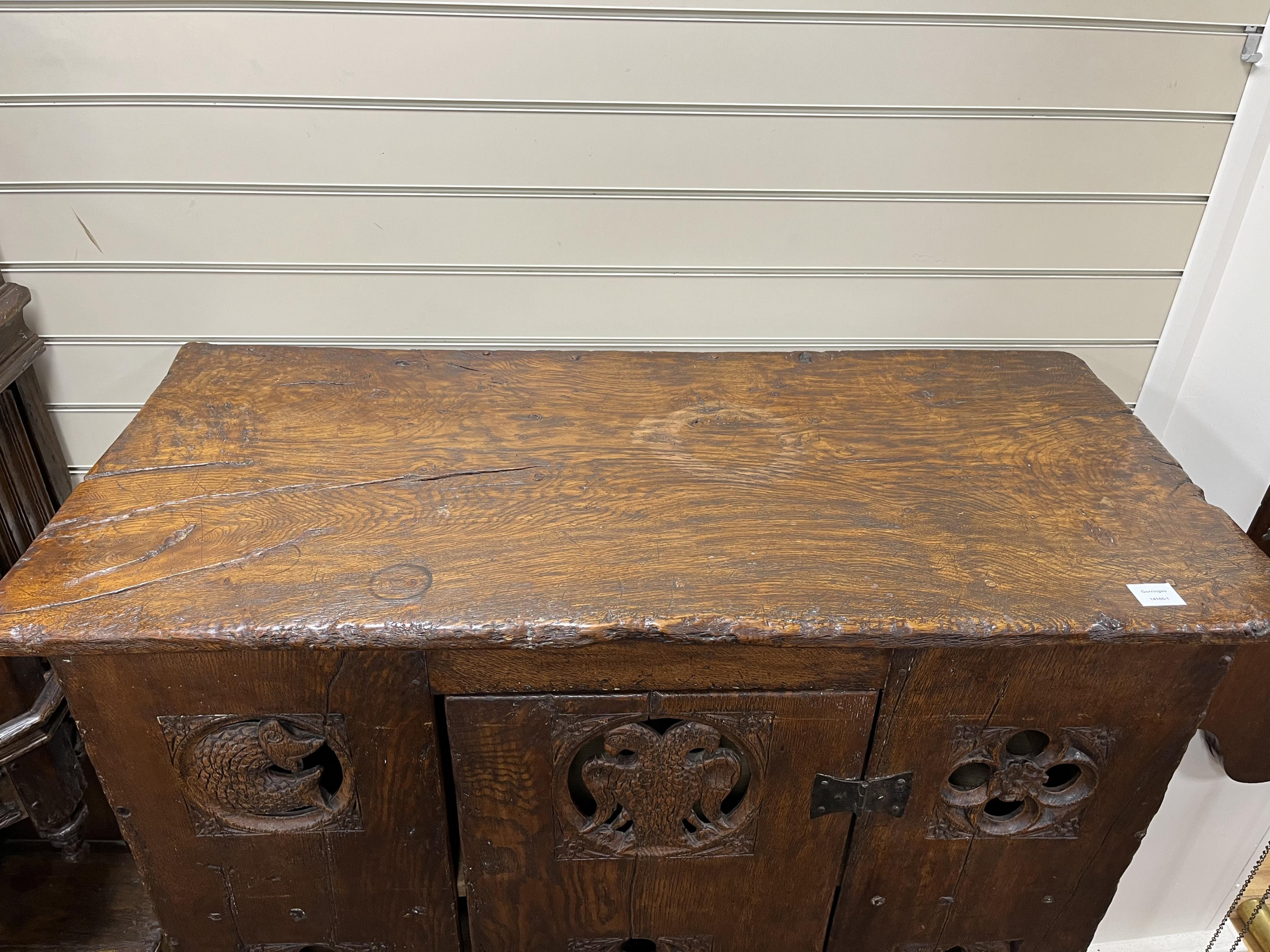 A boarded oak aumbry, in 16th century Tudor style, pierced and carved with armorial crests to the roundels, width 118cm, depth 55cm, height 114cm. Condition - fair to good, Provenance - made for Brede Place, Brede, Rye,